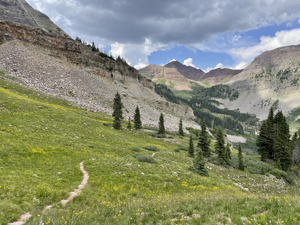 Finally reaching grass at the end of a seemingly never-ending scree slope near the end of our descent of North Maroon, a storm visibly brewing.